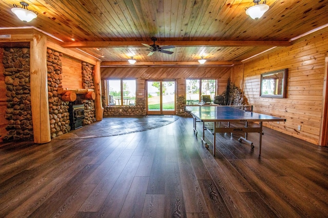 rec room featuring dark wood-type flooring, wooden ceiling, beam ceiling, and a wood stove