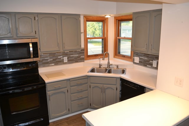 kitchen featuring tasteful backsplash, black appliances, gray cabinetry, and sink