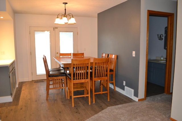 dining room with sink, dark hardwood / wood-style flooring, and an inviting chandelier