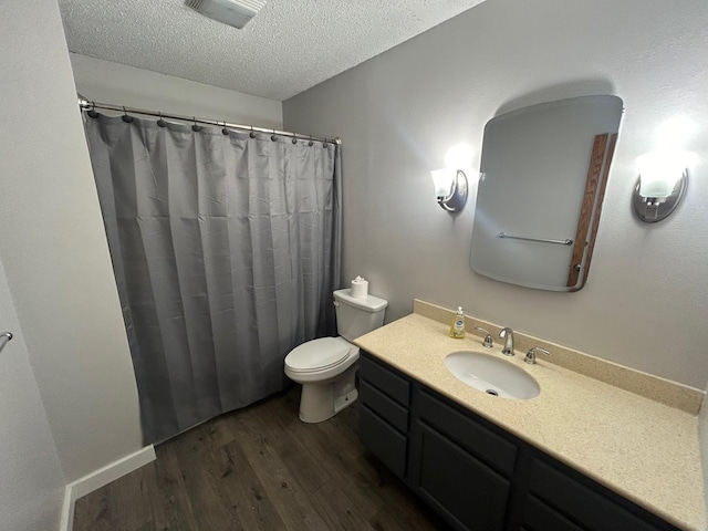 bathroom with toilet, wood-type flooring, vanity, and a textured ceiling