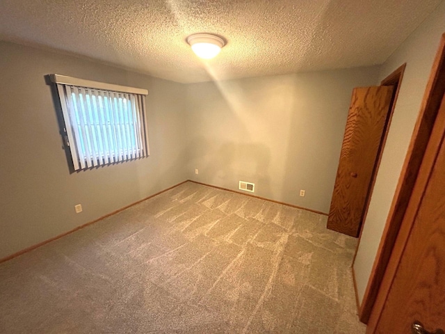 unfurnished room with a textured ceiling and light carpet