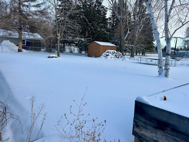 snowy yard with fence private yard, a storage shed, and an outbuilding