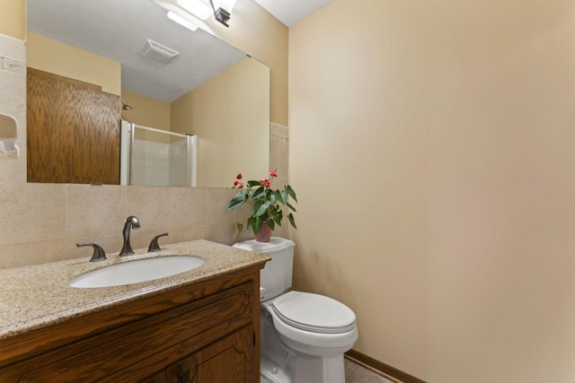 bathroom featuring vanity, toilet, tasteful backsplash, and walk in shower