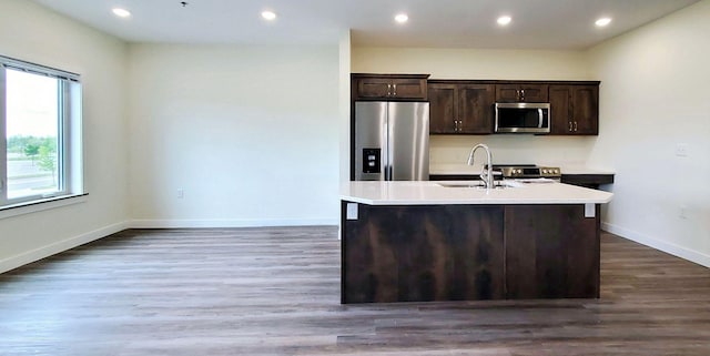 kitchen featuring appliances with stainless steel finishes, dark wood-type flooring, and an island with sink