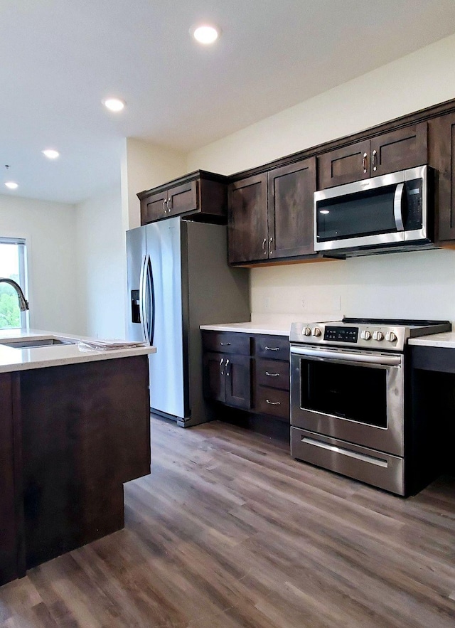 kitchen with sink, dark brown cabinets, appliances with stainless steel finishes, and wood-type flooring