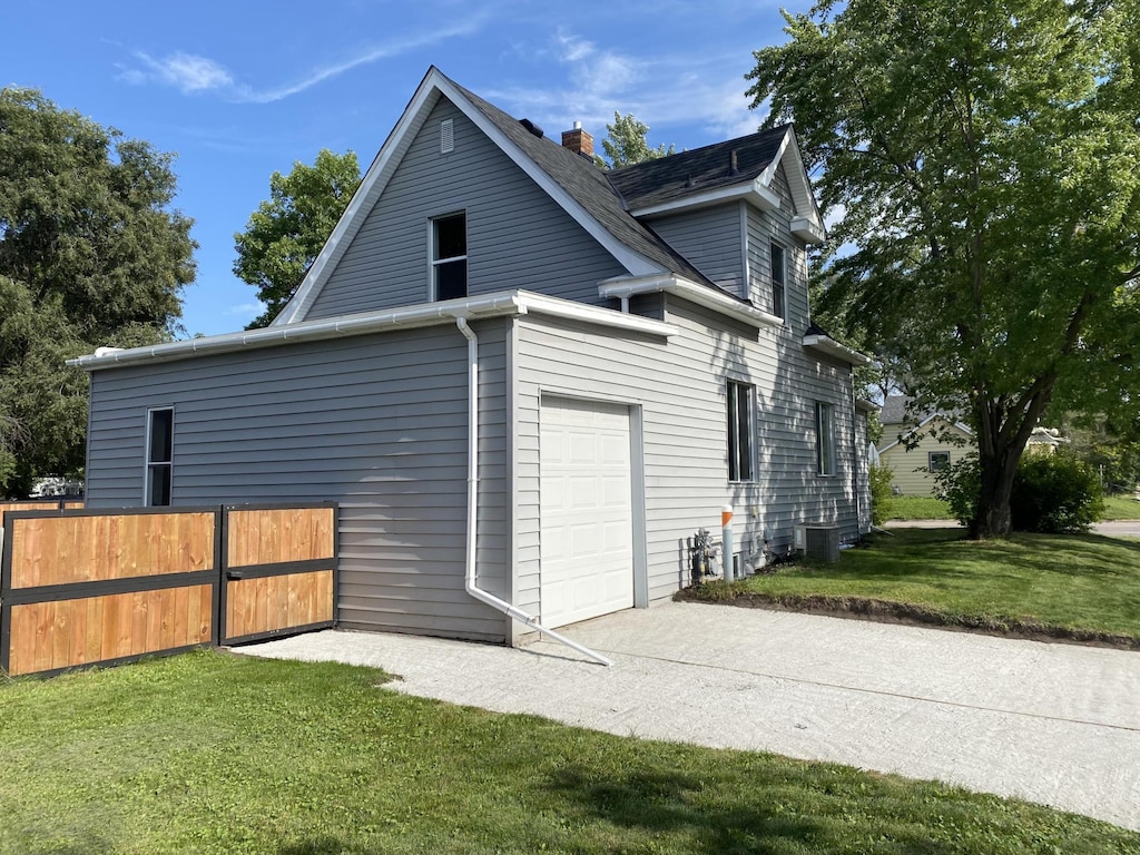 view of side of home featuring a lawn and central AC