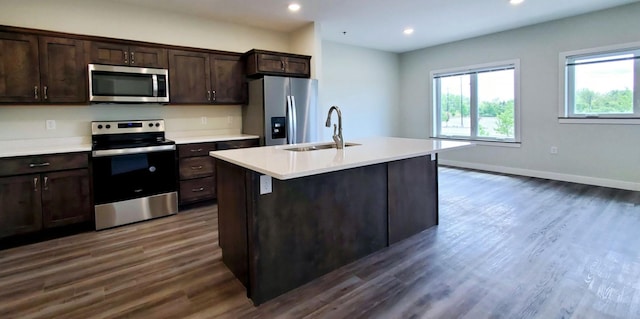 kitchen featuring stainless steel appliances, a kitchen island with sink, sink, dark hardwood / wood-style floors, and dark brown cabinetry