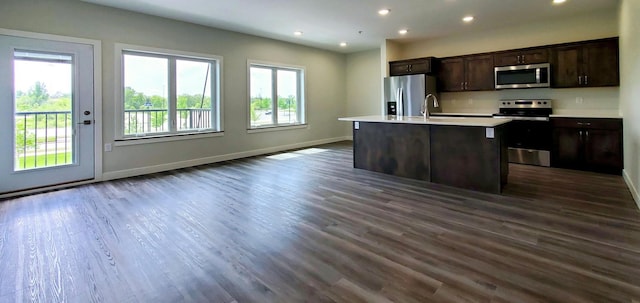 kitchen featuring sink, dark hardwood / wood-style floors, stainless steel appliances, and an island with sink