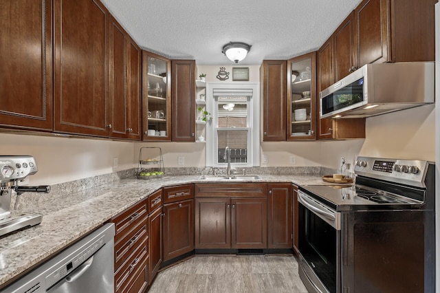 3509 43rd Ave S, Minneapolis, MN 55406 - kitchen featuring stainless steel appliances, a textured ceiling, light stone counters, glass insert cabinets, and light wood finished floors