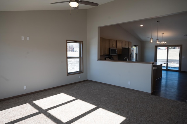 kitchen featuring appliances with stainless steel finishes, decorative light fixtures, and dark colored carpet