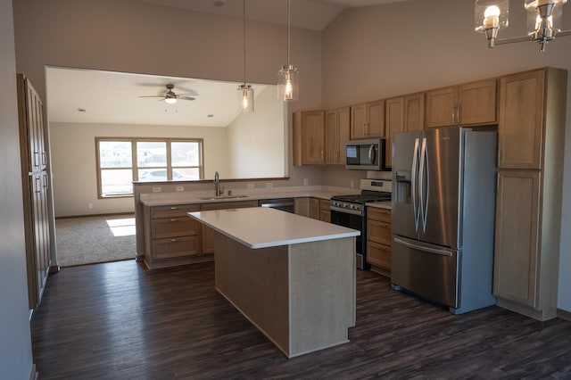 kitchen with sink, dark wood-type flooring, appliances with stainless steel finishes, hanging light fixtures, and a kitchen island