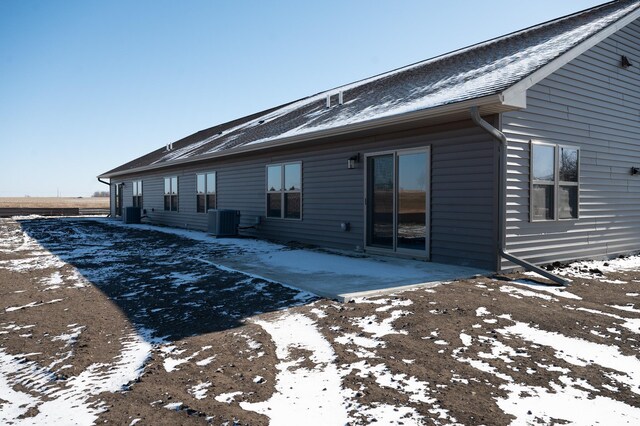 snow covered rear of property featuring a patio area and central air condition unit