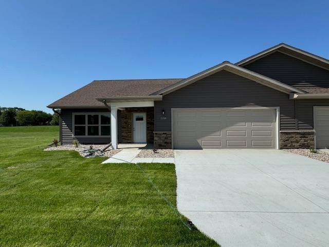 2218 Red Bird Ln, Fairmont, MN 56031 - view of front of house featuring an attached garage, driveway, a front yard, and stone siding