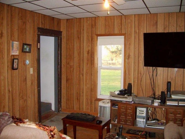 office featuring a drop ceiling and wood walls