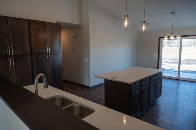 kitchen featuring sink, a kitchen island with sink, hanging light fixtures, dark hardwood / wood-style floors, and vaulted ceiling