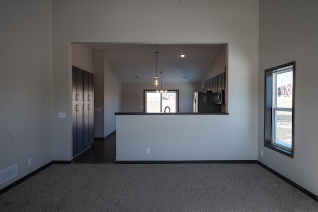 interior space featuring a wealth of natural light, a chandelier, vaulted ceiling, and dark colored carpet