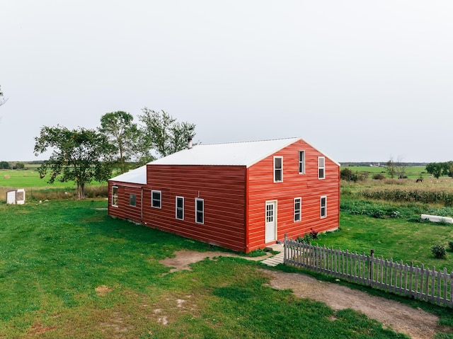 view of side of home with a lawn, an outdoor structure, and a rural view