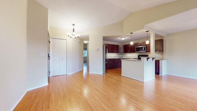 kitchen featuring pendant lighting, a kitchen island, appliances with stainless steel finishes, and light hardwood / wood-style flooring