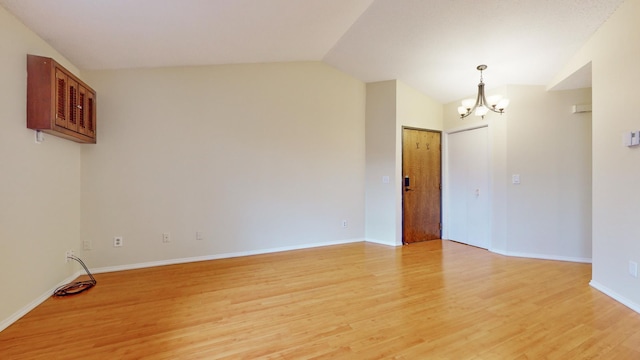 unfurnished room featuring light hardwood / wood-style floors, vaulted ceiling, and a notable chandelier