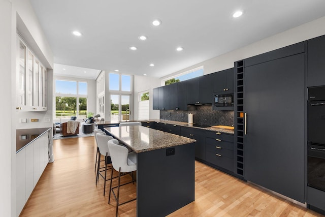 17680 Bearpath Trl, Eden Prairie, MN 55347 - kitchen featuring a breakfast bar area, modern cabinets, a center island, recessed lighting, and decorative backsplash