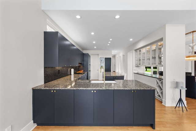 17680 Bearpath Trl, Eden Prairie, MN 55347 - kitchen with a peninsula, stone counters, light wood-style floors, recessed lighting, and glass insert cabinets