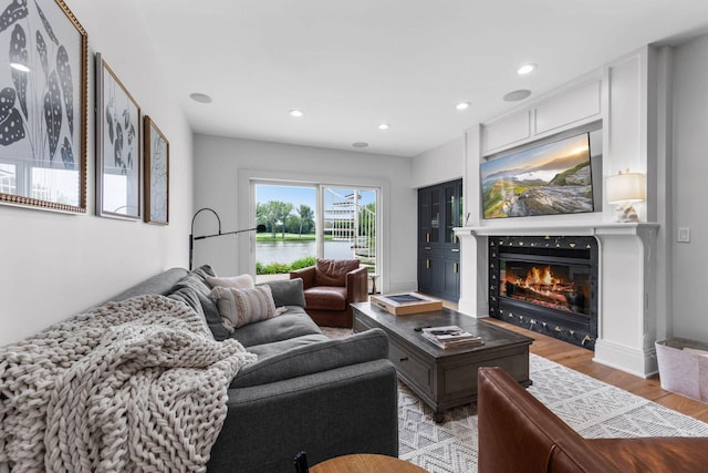 17680 Bearpath Trl, Eden Prairie, MN 55347 - living room featuring light wood-style flooring, a glass covered fireplace, a water view, and recessed lighting
