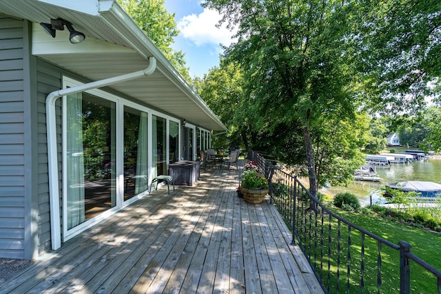 wooden terrace with a water view and a yard