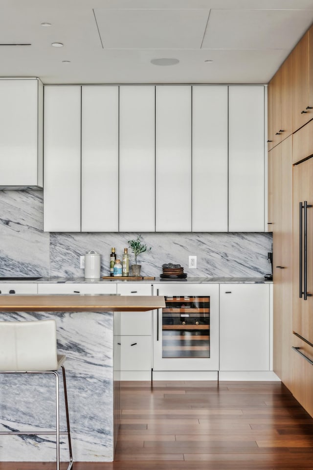 bar featuring beverage cooler, white cabinetry, hardwood / wood-style flooring, and tasteful backsplash