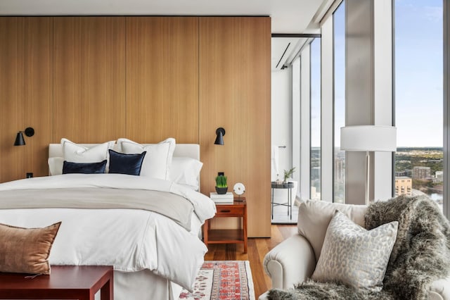 bedroom with floor to ceiling windows and light hardwood / wood-style floors