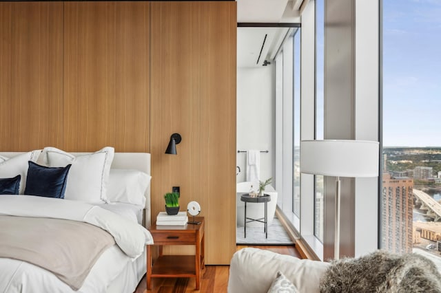 bedroom with a wall of windows and hardwood / wood-style flooring