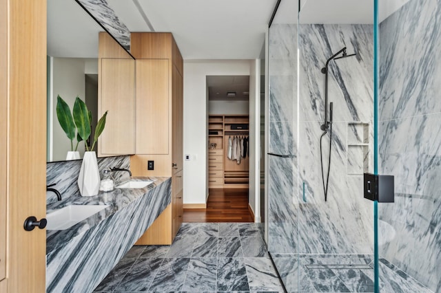 bathroom with a tile shower, vanity, and tile walls