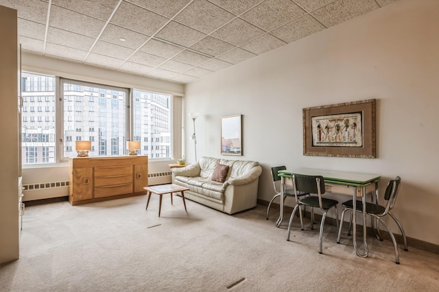 sitting room with a wealth of natural light, light colored carpet, and radiator