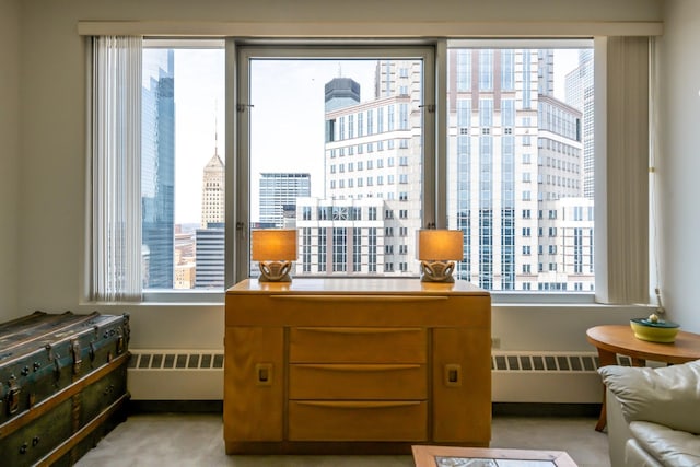 interior space featuring light colored carpet, multiple windows, and radiator