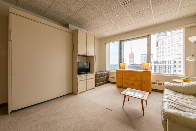 interior space featuring radiator, a paneled ceiling, and light carpet