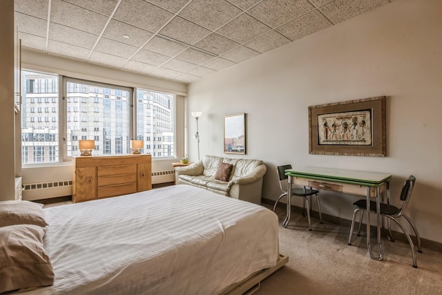 carpeted bedroom featuring radiator heating unit and a drop ceiling