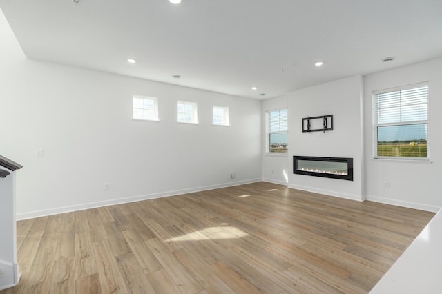 unfurnished living room featuring a wealth of natural light and light hardwood / wood-style floors