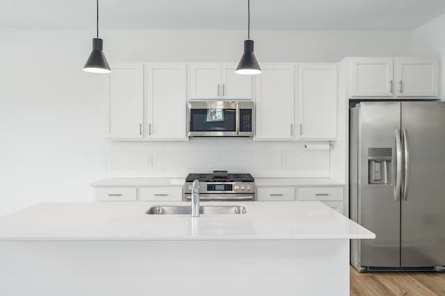 kitchen featuring appliances with stainless steel finishes, sink, light wood-type flooring, backsplash, and white cabinetry