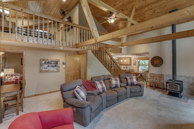 carpeted living room featuring wooden ceiling, a towering ceiling, ceiling fan, and a wood stove