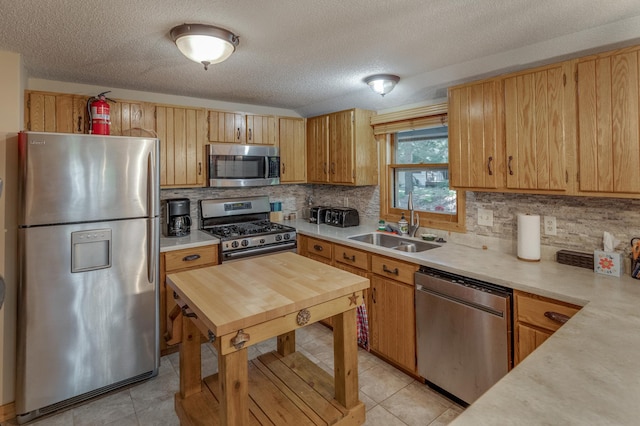 kitchen featuring a textured ceiling, light tile patterned flooring, sink, and stainless steel appliances