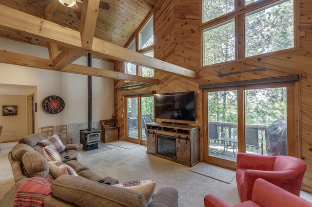 living room featuring wooden ceiling, wooden walls, light carpet, and a wood stove