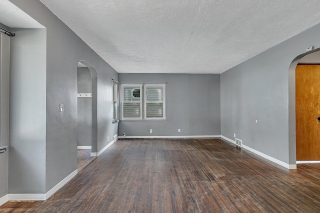 empty room with a textured ceiling and dark wood-type flooring