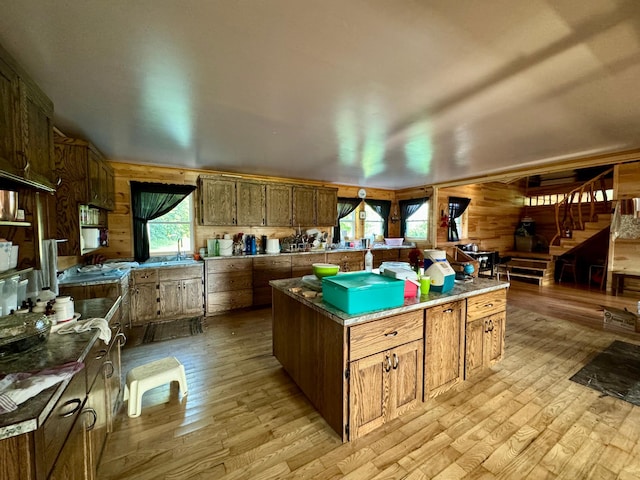 kitchen featuring light wood-type flooring, wood walls, a center island, and sink