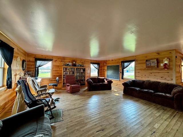 living room with a healthy amount of sunlight, wood-type flooring, and wood walls