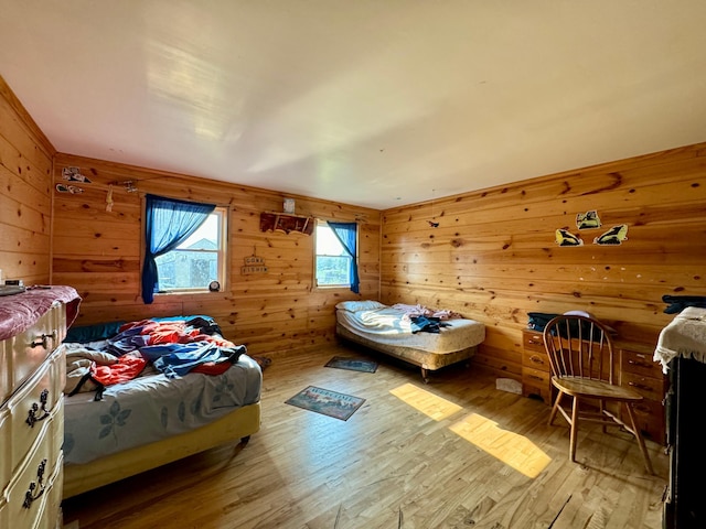 bedroom with wood walls and light hardwood / wood-style floors