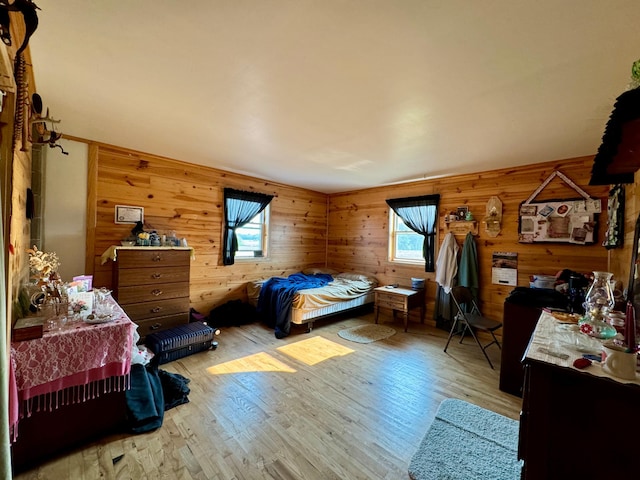 bedroom with multiple windows, wood-type flooring, and wood walls