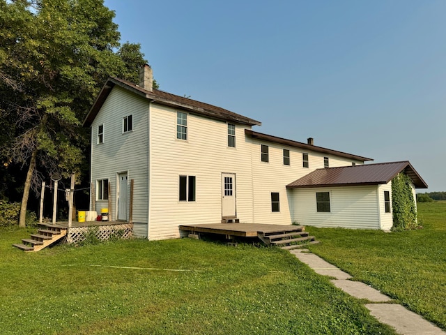 rear view of house with a deck, a lawn, and an outbuilding