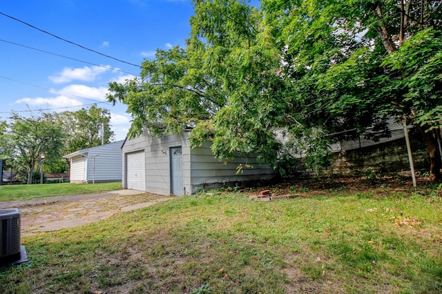 view of yard featuring driveway, a garage, and central AC unit