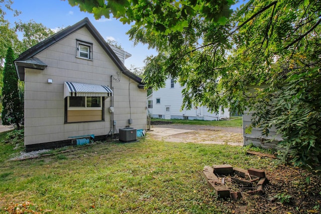 rear view of house with central AC and a lawn