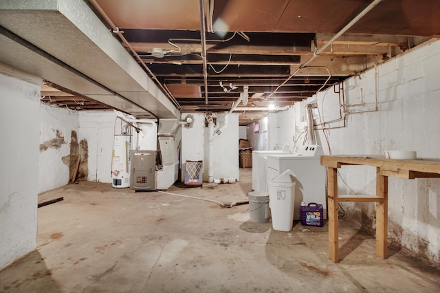 basement with gas water heater, heating unit, and washing machine and clothes dryer