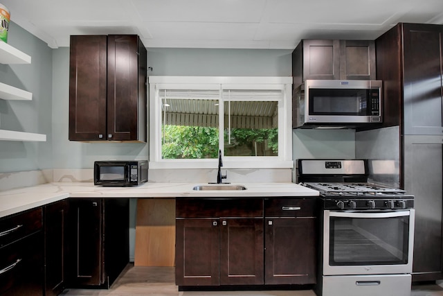 kitchen featuring light hardwood / wood-style floors, light stone counters, stainless steel appliances, dark brown cabinets, and sink